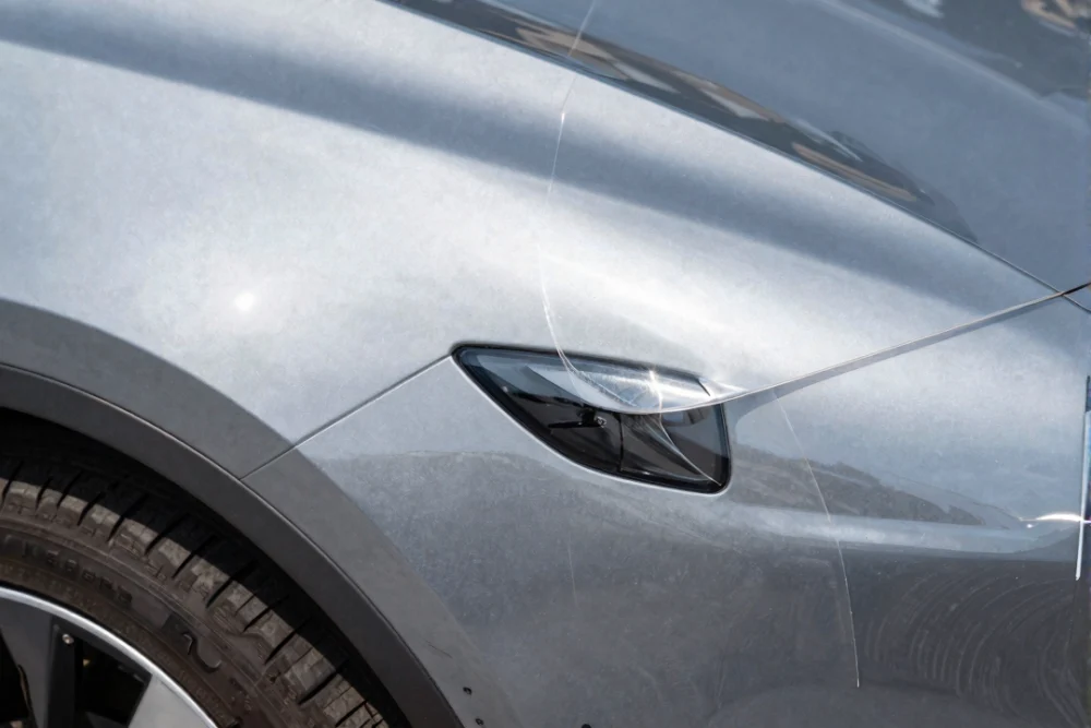 Car Sticker Printing Dubai: A Step-By-Step Guide 1 Close-up of a high-quality flexible vinyl sticker conforming to the curved surface of a car fender under bright sunlight.